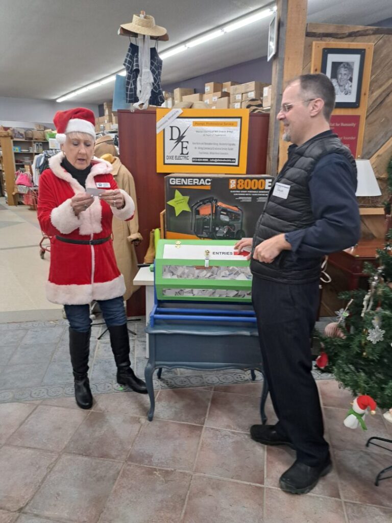 The moment the winner was announced: Mrs. Claus pictured beside a raffle drum with her elf helper